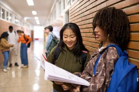 Two smiling students reviewing notes in university hallway Stock Photos