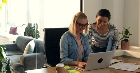 Two smiling young female professionals discussing business together over a  Stock Footage 88056939