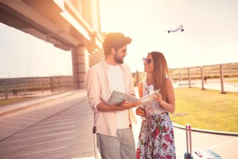 Two smiling young lovers walking from airport in town Stock Photos