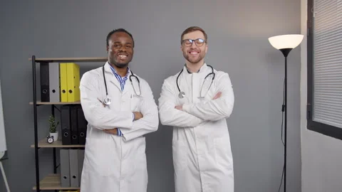 Two smilling doctors in white lab coats looking at camera in clinic 스톡 동영상 276224787