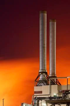 Two smoke stacks of a refinery with red steam. Stock Photos