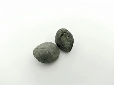 Two smooth, dark grey pebbles resting on a clean white background Stock Photos