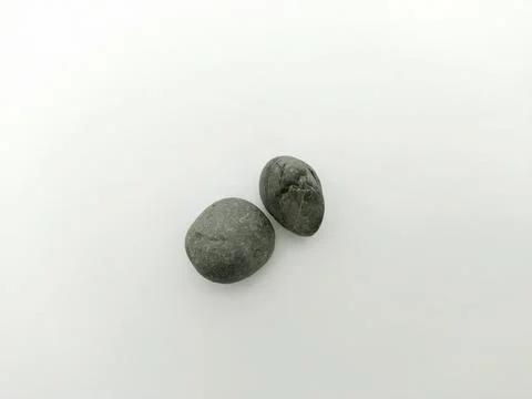 Two smooth, dark grey pebbles resting on a clean white background Stock Photos