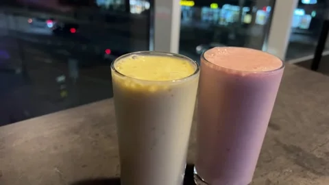 Two smoothies against the backdrop of the evening city on the table smoothie Stock Footage 292696513