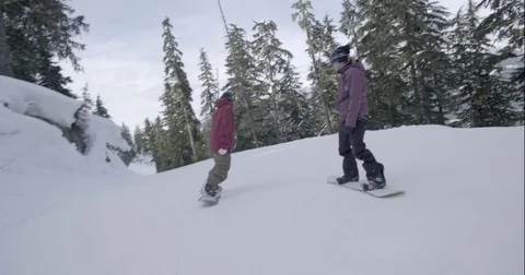 Two snowboarders beginning to skate over a snow clad mountain slope Stock Footage 80026036
