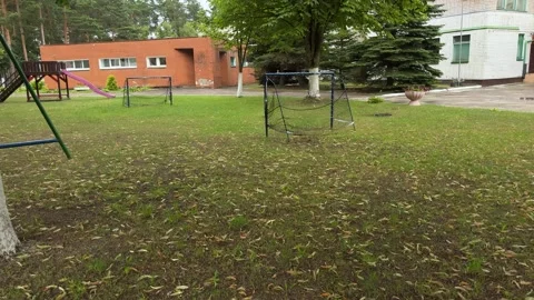 Two soccer goals with nets on grassy school field, buildings and trees 库存影片 340514921