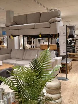 Two sofas displayed vertically on a frame inside a large department home stor Stock Photos