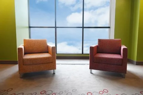 Two soft chairs in a large panoramic window. View of the sky and clouds. Stock Photos