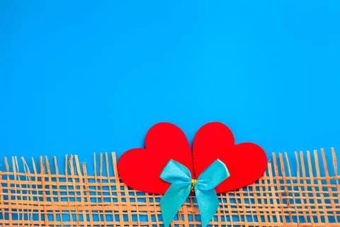 Two soft red hearts lying together on light blue knitted blanket plaid. Stock Photos