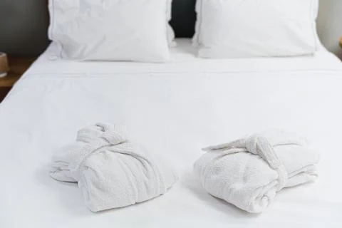 Two Soft White Bathrobes Placed On Clean Cozy White Bed Stock Photos