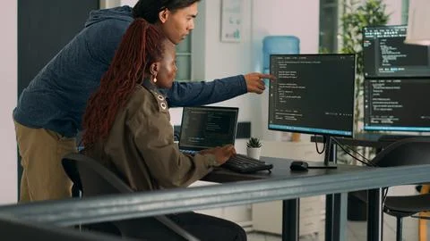 Two software coders analyzing source code on computer and laptop screen Stock Photos