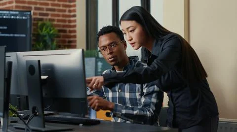 Two software developers coming at desk and sitting down holding laptop with Stock Photos
