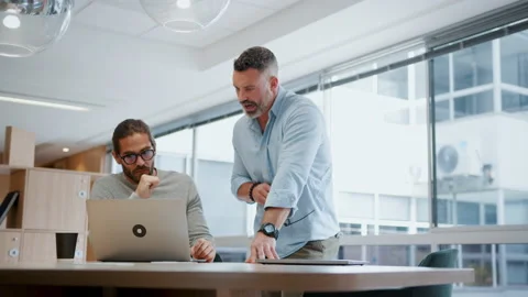 Two software developers discuss a solution to their project using a laptop Stock Footage 239086306