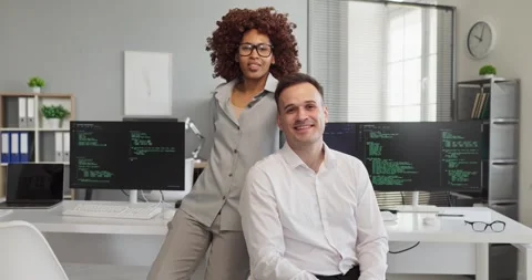 Two software developers in modern office, coding together by monitors with code Stock Footage 340169943