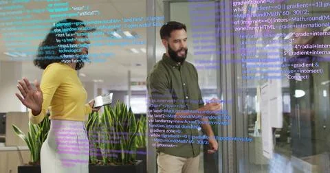 Two software engineers analyzing code on glass wall in office, using tablet Foto stock