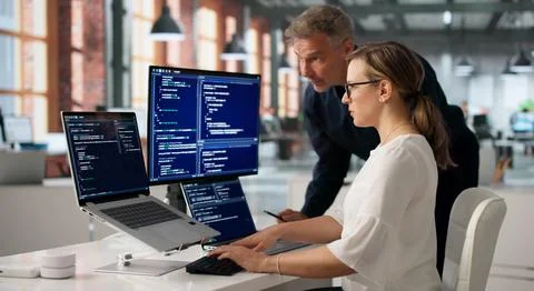 Two Software Engineers Discussing Secure Coding Solutions At Office Desk. Stock Photos