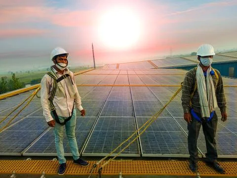 Two solar Engineers are standing on walkway and wearing safety harness, white Foto stock