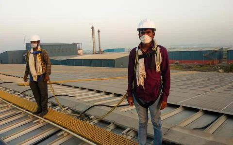Two solar Engineers are standing on walkway and wearing safety harness, white Foto stock