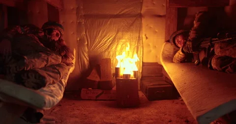 Two soldiers rest lying in a dugout in the light of a burning trench candle. Stock Footage 263297205