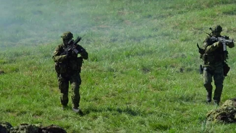 Two soldiers running through the smokey battlefield attacking and shooting with Stock Footage 337203874