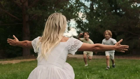 Two sons of different ages run to their mother and hug her. Stock Footage 217798116