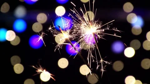 Two sparklers burning on black background with many colorful lights Stock Footage 132127826