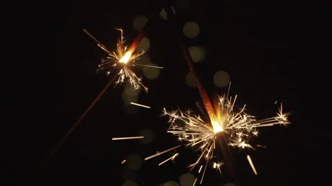 Two sparklers burning in the darkness with bokeh at background in 4x slow motion Stock Footage 146909332