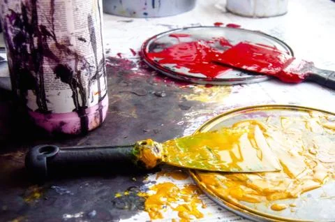Two spatulas in the paint on the table. Creative master mess. Working conditi Stock Photos