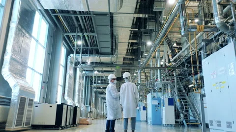 Two specialists in lab coats are walking through the factory unit. Factory Stock Footage 164653801