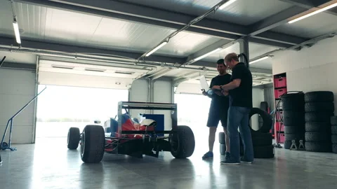 Two specialists with a laptop are talking next to the racing cart Stock Footage 162883567