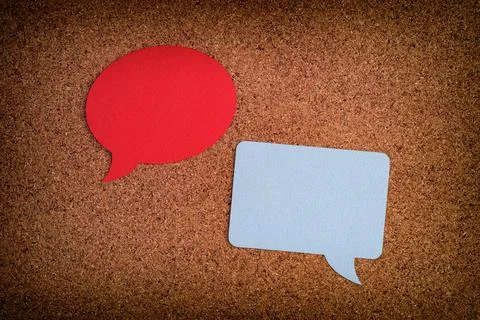 Two speech bubbles, one round, one square laying on a cork board Stock Photos