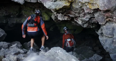 Two spelunkers walk into a dark cave in slow motion slider Stockbeeldmateriaal 64681081