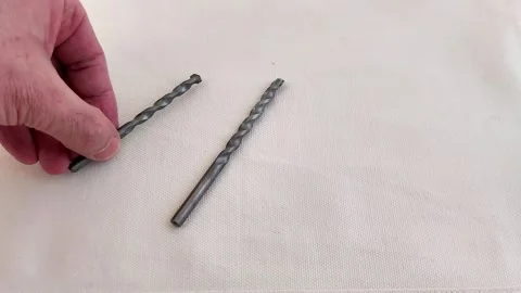 Two Spiral Drill Bits Resting on Light Fabric Background 스톡 동영상 321449975