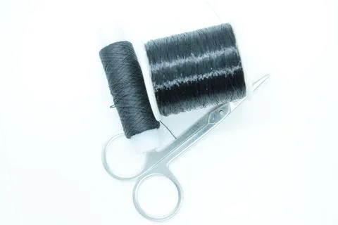 Two spools of black thread and scissors located on a white background Stock Photos