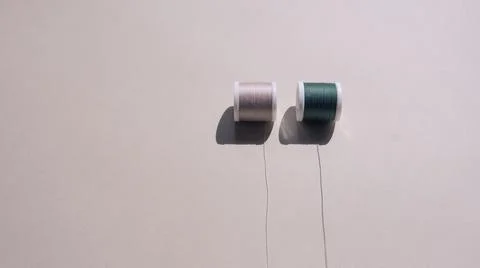 Two spools of sewing thread in pleasant beige and green on a harmonious sandy Stock Photos