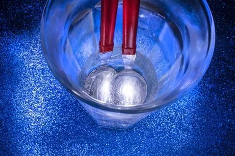 Two Spoons Shaking on Bottom of Blue Glass Stock Photos