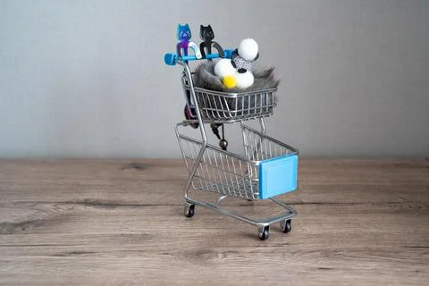 Two spoons in the shape of cat on the shopping cart, plush toy penguin  Stock Photos