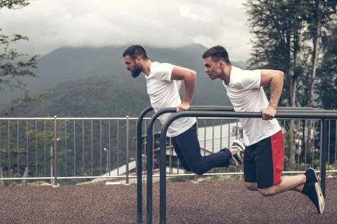 Two sportsmen doing dips on parallel bars Foto stock
