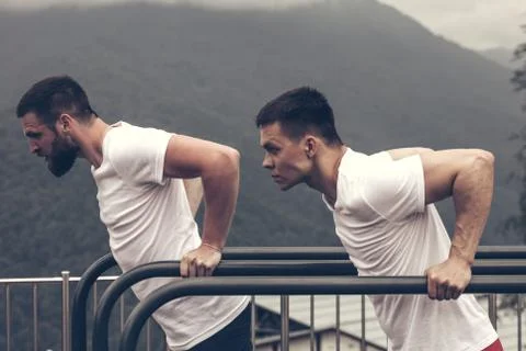 Two sportsmen doing dips on parallel bars Foto stock