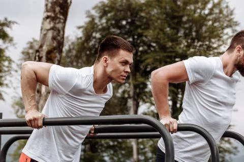 Two sportsmen doing dips on parallel bars Foto stock
