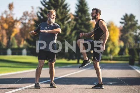 The two sportsmen doing exercise on the park alley Stock Photos