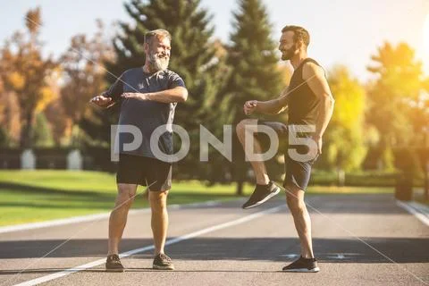 The two sportsmen doing exercise on the park alley on the sunset background Stock Photos