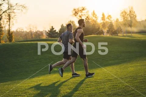 The two sportsmen running on the grass in the park Stock Photos