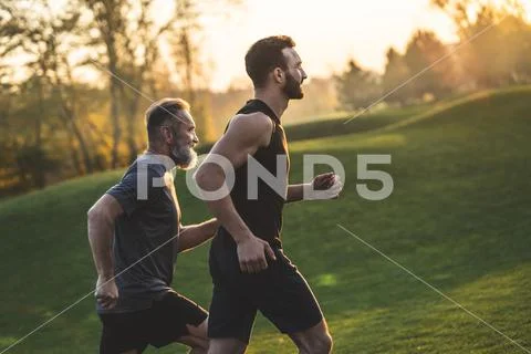 The two sportsmen running on the grass Stock Photos