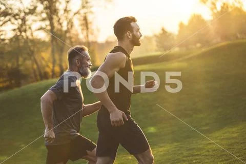 The two sportsmen running on the grass on the sunny background Stock Photos