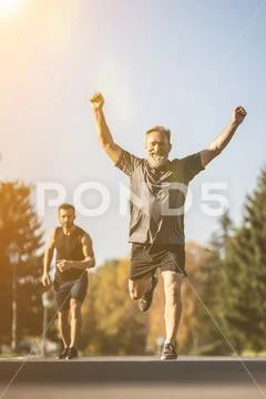 The two sportsmen running on the park road on the sunrise background Stock Photos