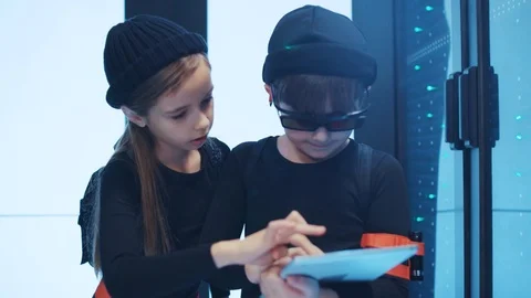 Two spy kids sneaking into server cabinet with digital laptop. Young team of Stock Footage 120696484