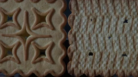 Two square butter cookies with wavy edges on dark background Stock Footage 332483437