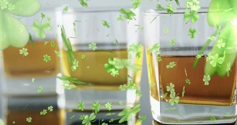 Two square glasses on glossy table while green clovers entering, drifting, Stock Footage 329928712