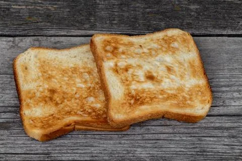 Two square ruddy pieces of bread for toasts on the old gray wooden background 스톡 사진